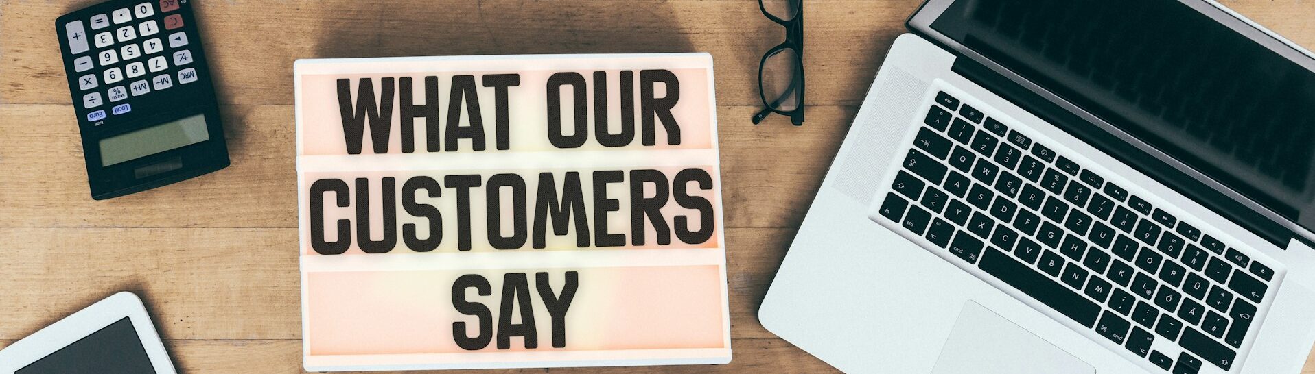 Customer testimonial message on light box at office desk with connected electronic devices